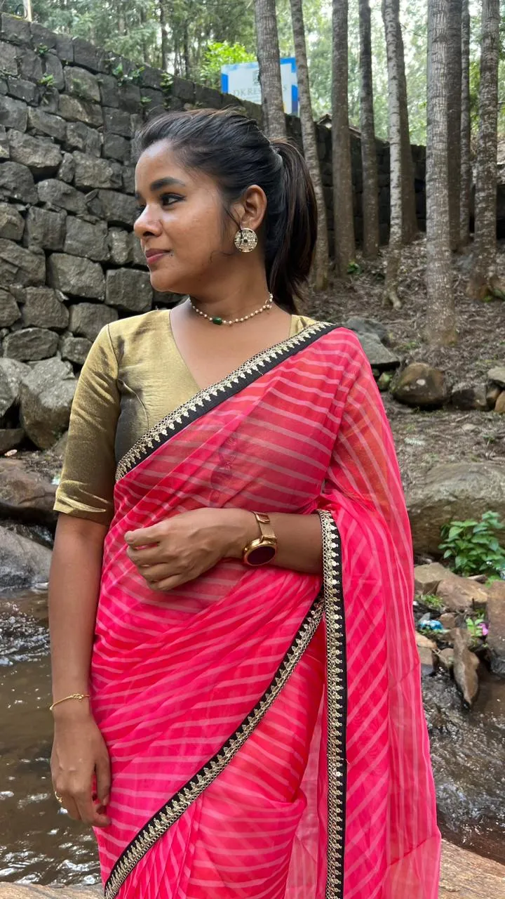 Pink stripped organza saree with black & gold blouse